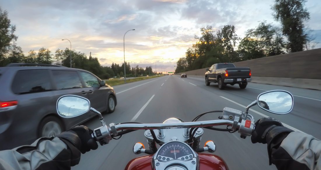 pov of a motorcycle driver driving along the road with cars.