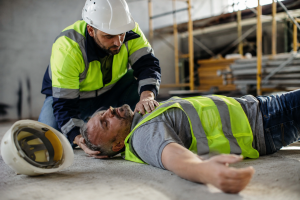Workplace accident with an injured construction worker receiving assistance, representing traumatic brain injuries (TBIs), head injuries, construction site accidents, and occupational safety hazards.