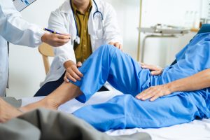 Doctors assess senior patient’s knee injury with care and teamwork in hospital. Hands-on medical treatment fosters recovery, trust, and healing.