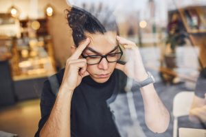 young guy with curly hair struggling to focus