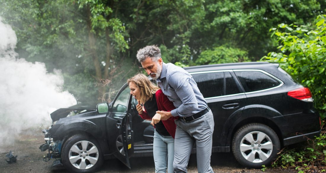 A mature man helping a young woman to walk after a car accident.