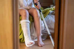 adult sitting with a leg cast on a bed