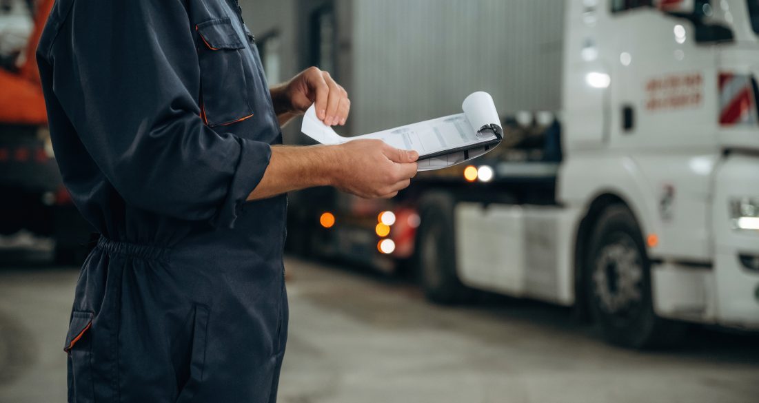Documents in notepad. Male worker is in the modern warehouse or manufacturing company.